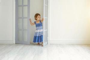 Little girl dancing in bright light living room at home and laughing photo