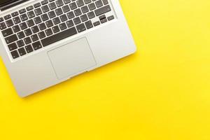 Keyboard laptop computer isolated on yellow desk background. Modern Information technology and sofware advances photo