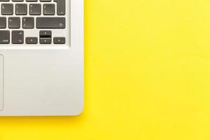 Keyboard laptop computer isolated on yellow desk background. Modern Information technology and sofware advances photo