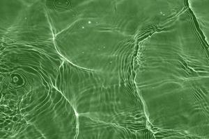 Defocus blurred transparent green colored clear calm water surface texture with splashes and bubbles. Trendy abstract nature background. Water waves in sunlight with copy space. Green water shine photo