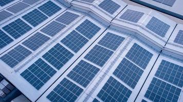 un grande solar célula techo en un industrial edificio generando electricidad para el planta durante tiempo de día según a políticas y medidas a reducir global calentamiento por tomando Angulo alto disparos desde drones foto