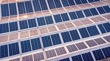 un grande solar célula techo en un industrial edificio generando electricidad para el planta durante tiempo de día según a políticas y medidas a reducir global calentamiento por tomando Angulo alto disparos desde drones foto