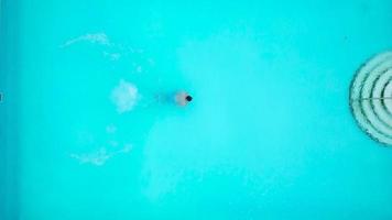 View from the top as a man jumping and dives into the pool and swims under the water video