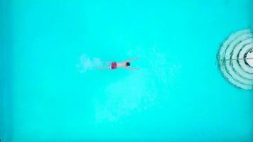 View from the top as a man jumping and dives into the pool and swims under the water video