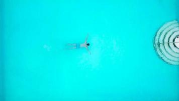 View from the top as a man jumping and dives into the pool and swims under the water video