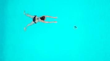 vue de le Haut comme une femme sauter et plongées dans le bassin et nage en dessous de le l'eau video