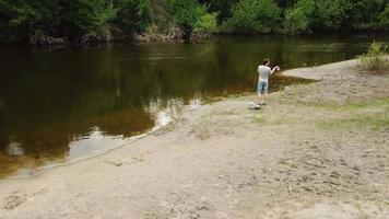 pescador con un pescar varilla en el río banco. hombre pescador capturas un pescado video