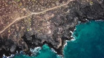 topp se av en folktom kust. klippig Strand av de ö av teneriffa. antenn Drönare antal fot av hav vågor nå Strand video