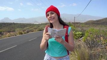 Traveler woman hitchhiking on a sunny road and walking. Backpacker woman looking for a ride to start a journey on a sunlit country road. Slow motion video