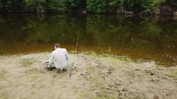 pescador con un pescar varilla en el río banco. hombre pescador capturas un pescado video