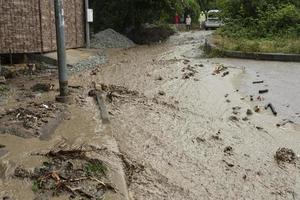 un natural desastre de inundación, lodoso corrientes de agua con piedras y barro en el calles de el ciudad. foto