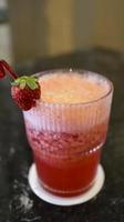 A glass of strawberry juice at the table with a fancy straw. photo