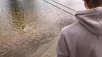 Fischer mit ein Angeln Stange auf das Fluss Bank. Mann Fischer fängt ein Fisch video