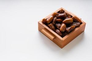 Dried dates fruit in wooden tray with soft napkin isolated on white background. photo