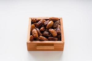 Dried dates fruit in wooden tray with soft napkin isolated on white background. photo