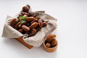 Dried dates fruit in wooden tray with soft napkin isolated on white background. photo