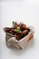 Dried dates fruit in wooden tray with soft napkin isolated on white background. photo