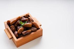 Dried dates fruit in wooden tray with soft napkin isolated on white background. photo
