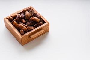 Dried dates fruit in wooden tray with soft napkin isolated on white background. photo