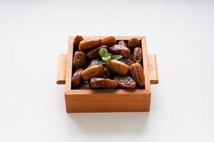 Dried dates fruit in wooden tray with soft napkin isolated on white background. photo