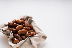 Dried dates fruit in wooden tray with soft napkin isolated on white background. photo