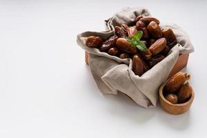 Dried dates fruit in wooden tray with soft napkin isolated on white background. photo