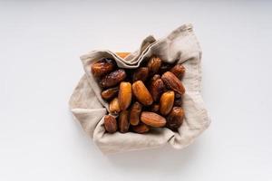 Dried dates fruit in wooden tray with soft napkin isolated on white background. photo
