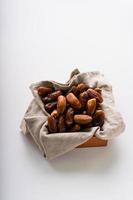 Dried dates fruit in wooden tray with soft napkin isolated on white background. photo