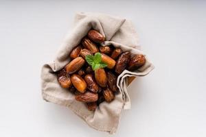 Dried dates fruit in wooden tray with soft napkin isolated on white background. photo