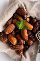 Dried dates fruit in wooden tray with soft napkin isolated on white background. photo