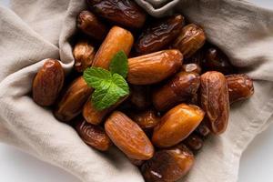 Dried dates fruit in wooden tray with soft napkin isolated on white background. photo