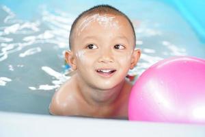 Hot weather. Boy playing with water happily in the tub. photo