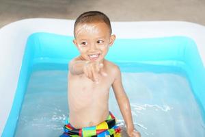 caliente clima. chico jugando con agua felizmente en el tina. foto