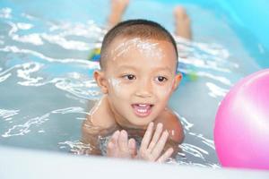 Hot weather. Boy playing with water happily in the tub. photo