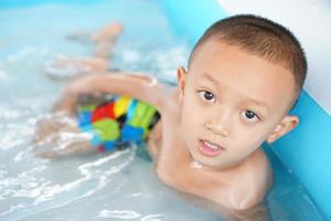 Hot weather. Boy playing with water happily in the tub. photo