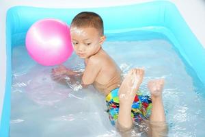 Hot weather. Boy playing with water happily in the tub. photo