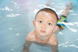 Hot weather. Boy playing with water happily in the tub. photo