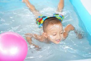 Hot weather. Boy playing with water happily in the tub. photo