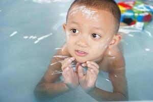 Hot weather. Boy playing with water happily in the tub. photo