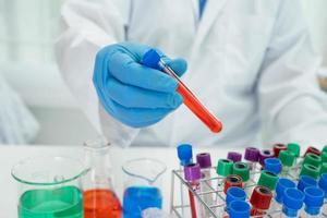 Scientist holding erlenmeyer flask, conical flask glassware with red color liquid solution in science chemistry laboratory. photo