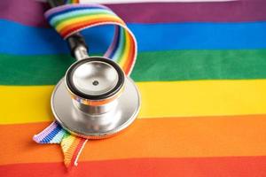 Black stethoscope on rainbow flag background, symbol of LGBT pride month celebrate annual in June social, symbol of gay, lesbian, bisexual, transgender, human rights and peace. photo