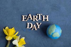 Earth day text with globe and flowers. Happy Earth day concept flat lay, top view photo