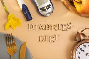 Diabetes diet text. A glucometer and a plate with cutlery on colored background flat lay, top view photo