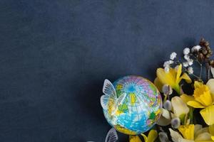 Globe, flowers and butterfly with copy space. Happy Earth day concept flat lay, top view. photo