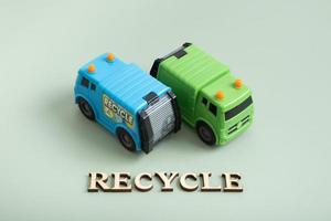 Recycle text. Toy garbage trucks and recycle text on a green background photo