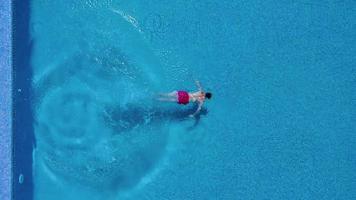 View from the top as a man jumping and dives into the pool and swims under the water video