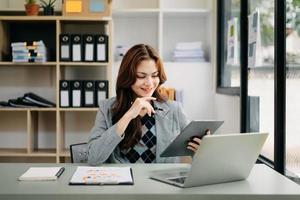 la mujer independiente está trabajando en su trabajo en una tableta de computadora y una computadora portátil haciendo un informe de análisis contable de datos de inversión inmobiliaria, financieros foto