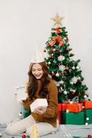 Asian young happy girl kid and decorate Christmas tree. Young little adorable child to celebrate holiday Xmas thanksgiving party  in house. photo