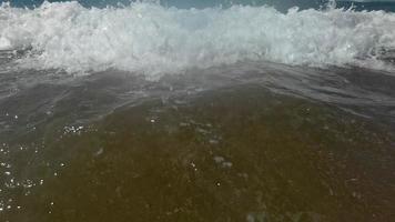 lento movimento do ampla onda quebra em a de praia com espuma e surfar video