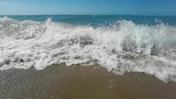 lento movimento di grande onda rottura su il spiaggia con schiuma e Surf video